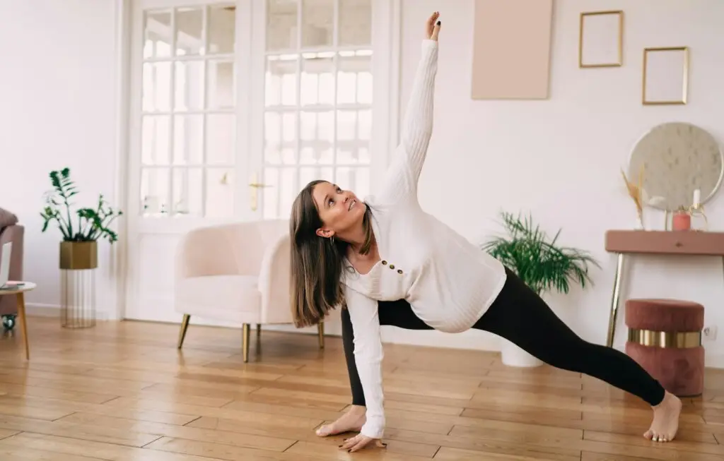 Healthy pregnancy tip shows smiling pregnant female mom doing extended side angle poses while practicing yoga