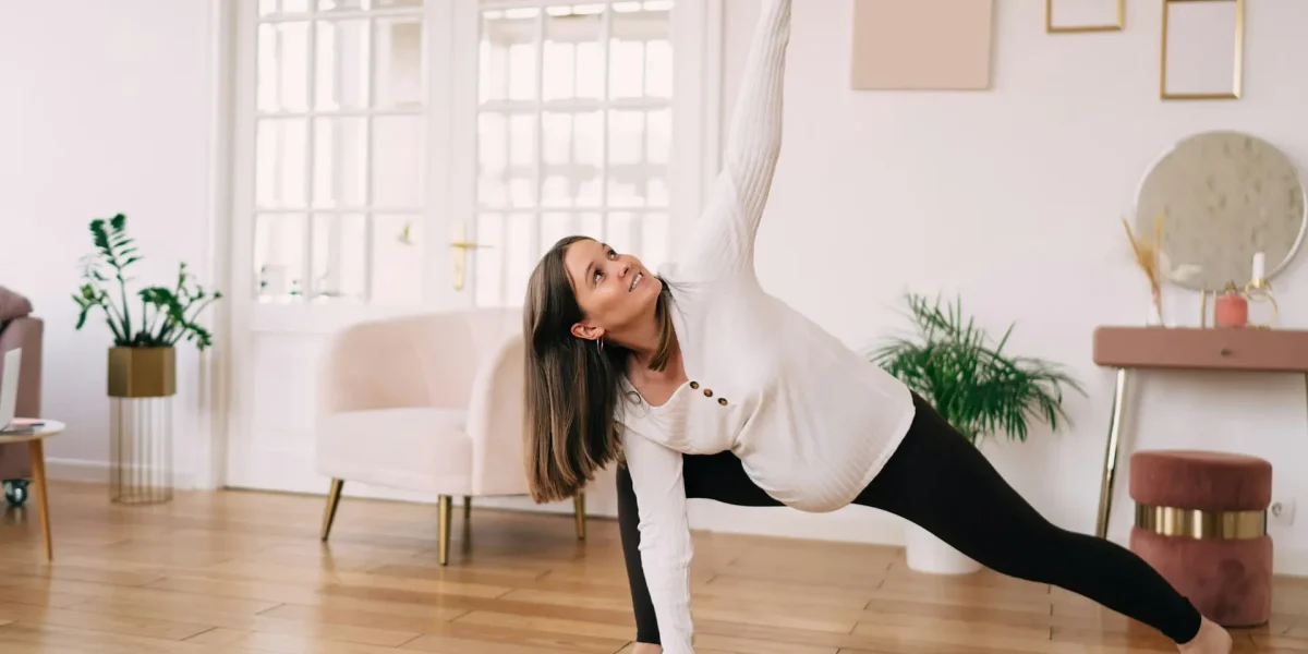 Healthy pregnancy tip shows smiling pregnant female mom doing extended side angle poses while practicing yoga